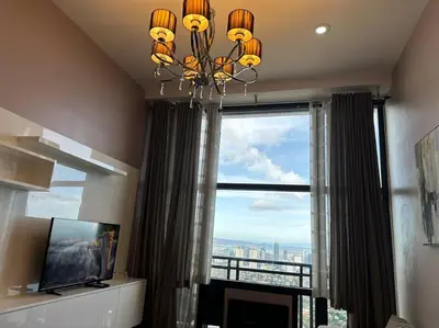 a living room with a chandelier and a large window at 68F 1 Bedroom Penthouse Suite Gramercy Pool Sauna in Manila