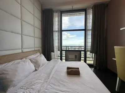 a bedroom with a white bed with a large window at 68F 1 Bedroom Penthouse Suite Gramercy Pool Sauna in Manila