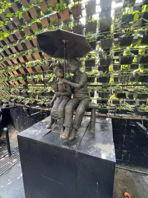 a statue of a couple sitting on a bench with an umbrella at 45F Gramercy Corner Studio Wifi Netflix SmartTV free use Pool Gym in Manila