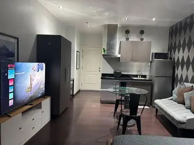 a living room with a tv and a table and a kitchen at Penthouse Studio Highspeed Wi Fi Smart TV Pool GYM in Manila