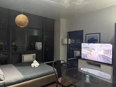 a living room with a tv and a glass table at Penthouse Studio Highspeed Wi Fi Smart TV Pool GYM in Manila
