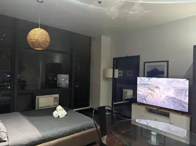 a bedroom with a bed and a flat screen tv at Penthouse Studio Highspeed Wi Fi Smart TV Pool GYM in Manila