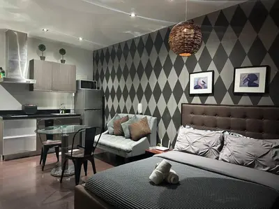 a living room with a bed and a table and a kitchen at Penthouse Studio Highspeed Wi Fi Smart TV Pool GYM in Manila
