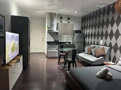 a living room with a couch and a table and a kitchen at Penthouse Studio Highspeed Wi Fi Smart TV Pool GYM in Manila