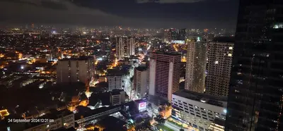 a view of a city at night with lights at Makati Bliss Apartment - Cozy Urban Retreat in Manila