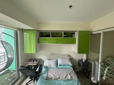 a bedroom with a bed and a desk and a window at Azure Apartment in Manila