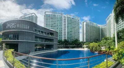 a resort with a swimming pool in front of a building at Azure Apartment in Manila