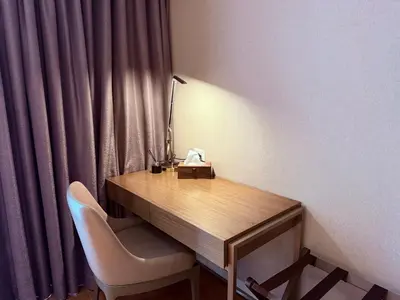 a desk with a lamp and a chair in a room at Novotel Residences ACQUA near Rockwell Makati in Manila
