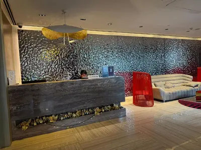a lobby with a couch and a wall with a painting at Novotel Residences ACQUA near Rockwell Makati in Manila