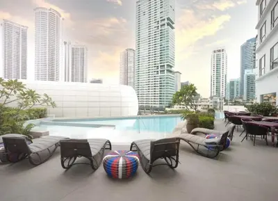 a swimming pool with chairs and tables in a city at Novotel Residences ACQUA near Rockwell Makati in Manila