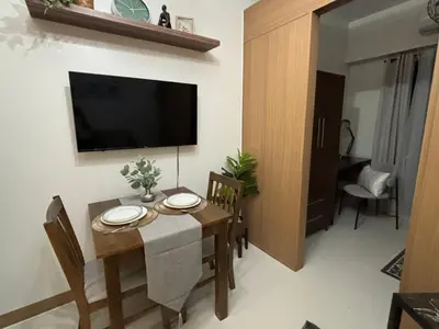 a dining room with a table and a television on a wall at Cozy Space in Makati - Margareth Suite in Manila
