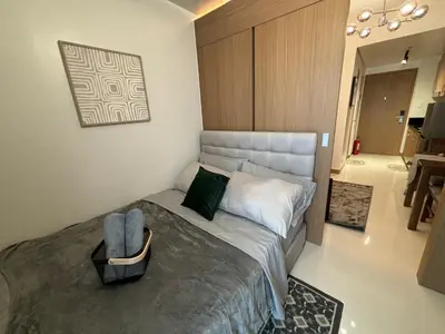 a bedroom with a bed with a chair and a bathroom at Cozy Space in Makati - Margareth Suite in Manila