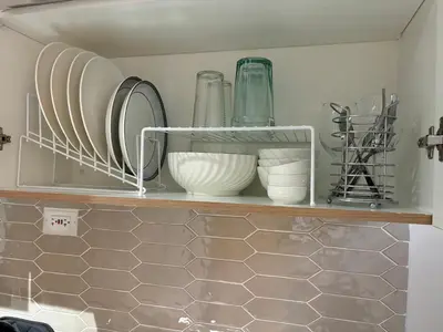 a shelf with plates and bowls on it in a kitchen at Cozy Space in Makati - Margareth Suite in Manila