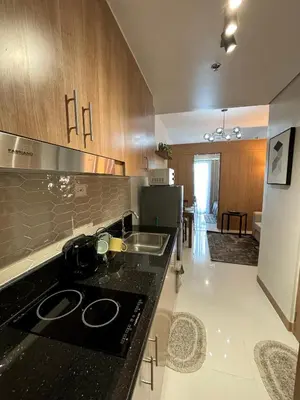 a kitchen with a black counter top and a sink at Cozy Space in Makati - Margareth Suite in Manila