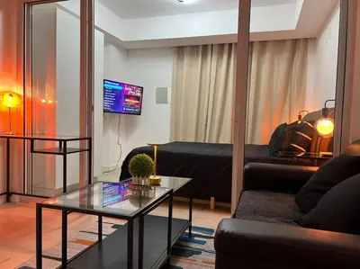 a living room with a black couch and a table at Azure Playfull Living 1 bedroom in Manila