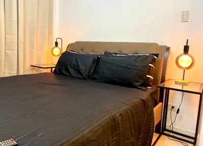 a bedroom with a bed with two lamps on tables at Azure Playfull Living 1 bedroom in Manila