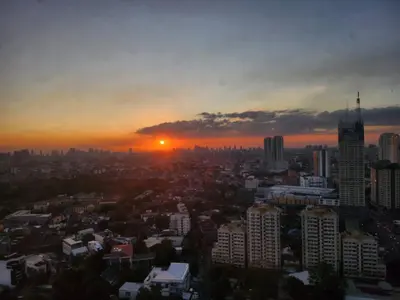a city skyline with the sun setting in the sky at Cozy Studio Unit Near MRT Shaw & Malls in Manila