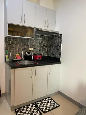 a kitchen with white cabinets and a counter top at Marlouise Place Beacon T1 in Manila