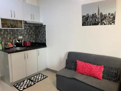 a kitchen with a couch with a red and black pillow at Marlouise Place Beacon T1 in Manila