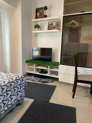 a room with a tv and a bed and a table at Marlouise Place Beacon T1 in Manila