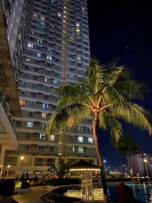 a palm tree in front of a large building at Marlouise Place Beacon T1 in Manila