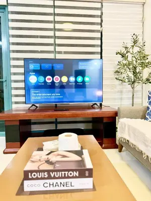 a living room with a television and a book on a coffee table at COZI two bedroom family room near Grand Hyatt BGC in Manila