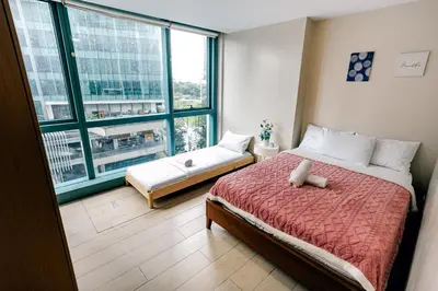 a bedroom with a bed and a large window at COZI two bedroom family room near Grand Hyatt BGC in Manila
