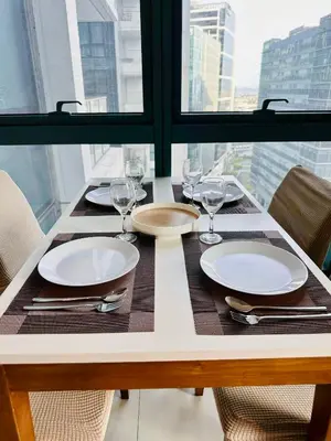 a table with plates and glasses on a table with a window at COZI two bedroom family room near Grand Hyatt BGC in Manila