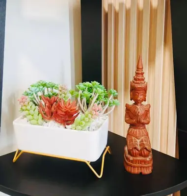 a table with a planter with flowers and a statue at Condo Staycation - Kanlungan by Anna at Satori Residences, Pasig in Manila