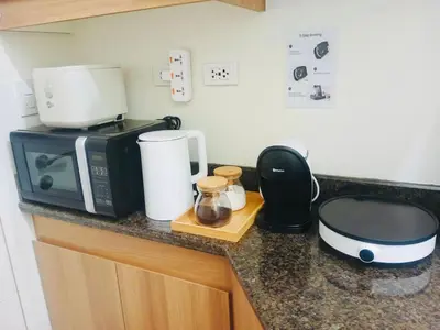 a kitchen counter with a coffee maker and a microwave at Condo Staycation - Kanlungan by Anna at Satori Residences, Pasig in Manila
