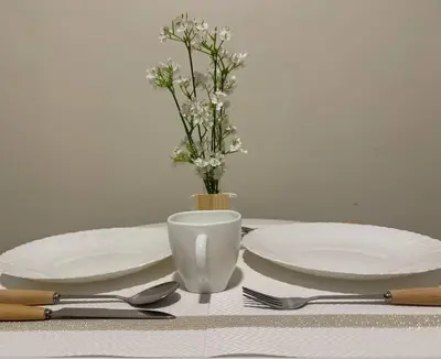 a table with two plates and a vase with flowers at Cozy 1BR nr Ortigas Makati & BGC with Secured Parking in Manila