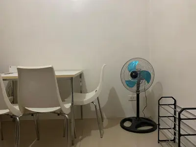 a desk with a fan next to a table with chairs at CASSa LISHA in Manila