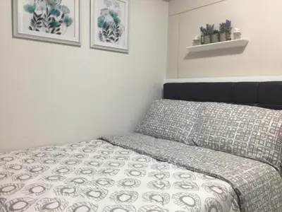 a small bedroom with a bed and some pictures on the wall at 7J HomeStay at Sea Residences MoA Manila in Manila
