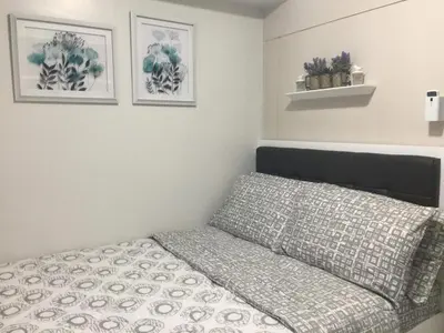 a bed in a bedroom with two pictures on the wall at 7J HomeStay at Sea Residences MoA Manila in Manila