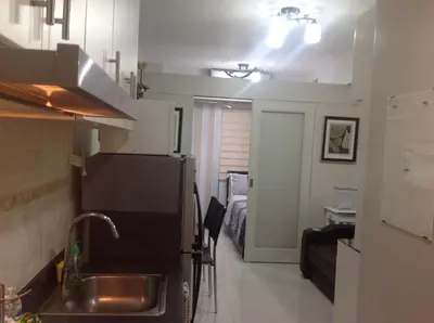 a kitchen with a sink and a refrigerator in a room at 7J HomeStay at Sea Residences MoA Manila in Manila