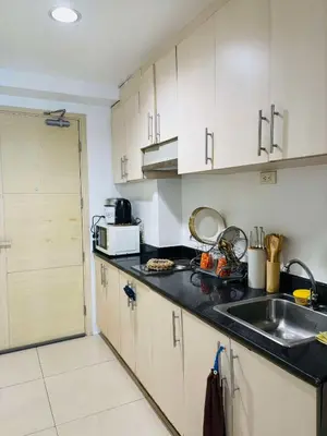 a kitchen with white cabinets and a sink at Flores Place At Sea Residences MOA in Manila