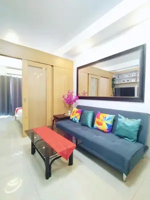 a living room with a blue couch and a table at Comfystay at Shell Residences in Manila