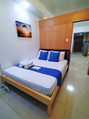 a bedroom with a large bed with blue pillows at Comfystay at Shell Residences in Manila