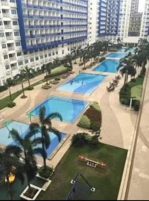 an overhead view of a large pool with palm trees and buildings at Sea Residences Condo SM Mall of Asia Entertainment District in Manila