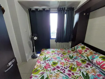 a bedroom with a bed with a floral bedspread and a window at Sea Residences Condo SM Mall of Asia Entertainment District in Manila