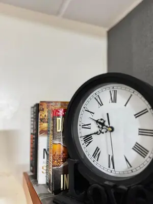 a clock sitting on a shelf next to books at VR Homes Ortigas - 2BR Condo with Free WiFi & Netflix in Manila