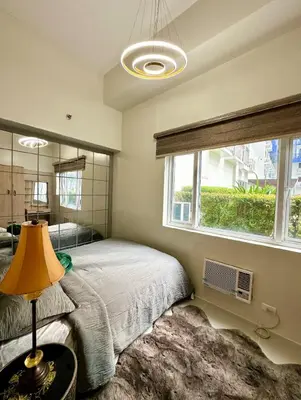 a bedroom with a bed and a large window at Suite 101F a New & Spacious MOA Sunrise Drive Oasis in Manila