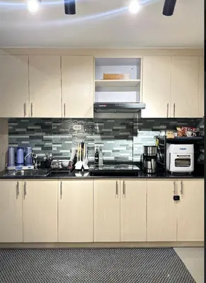 a kitchen with white cabinets and a black counter top at Suite 101F a New & Spacious MOA Sunrise Drive Oasis in Manila