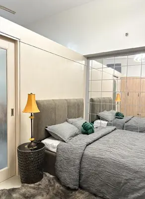 a bedroom with a bed and a lamp and a mirror at Suite 101F a New & Spacious MOA Sunrise Drive Oasis in Manila