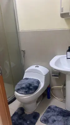 a bathroom with a toilet and a sink with blue rugs at 1Bdrm Condo at Makati w Balcony view of Mnla Bay in Manila