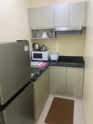 a small kitchen with a refrigerator and a microwave at 1Bdrm Condo at Makati w Balcony view of Mnla Bay in Manila