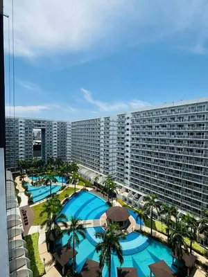 a large apartment building with two pools and palm trees at Condotel By RhoiVC in Shell Residences Moa Near Naia Airport in Manila