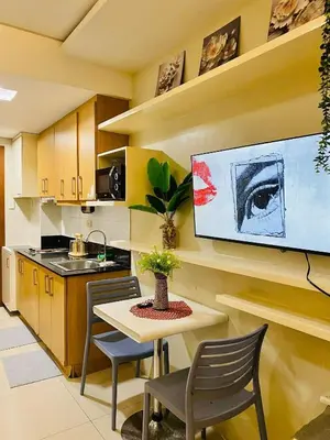 a kitchen with a table and chairs and a tv at Condotel By RhoiVC in Shell Residences Moa Near Naia Airport in Manila