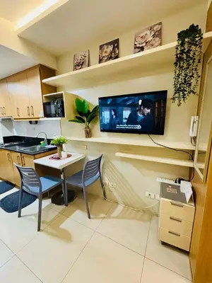 a kitchen with a table and a tv on the wall at Condotel By RhoiVC in Shell Residences Moa Near Naia Airport in Manila