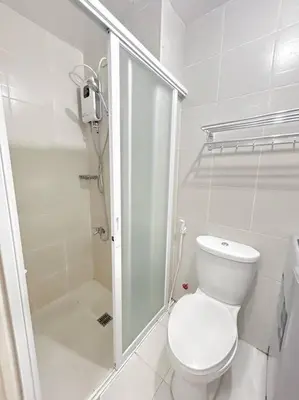 a white bathroom with a toilet and a shower at Jazz Residences Tower D 1BR in Manila